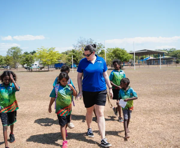 A woman walks along the grass with the children