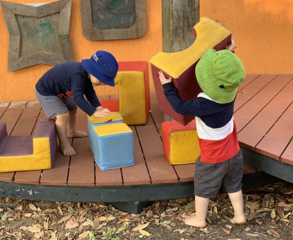 2 children playing with foam blocks outside