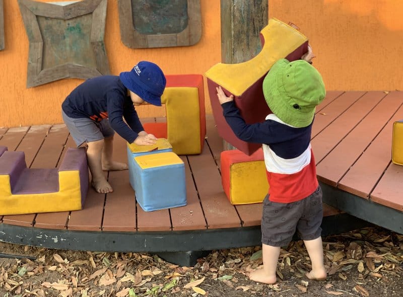 2 children playing with foam blocks outside