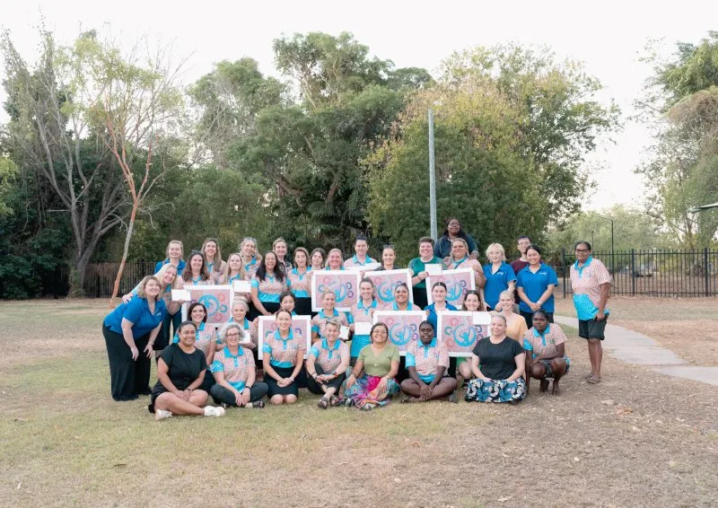 A group of people smile for a photo abnd hold up a photo
