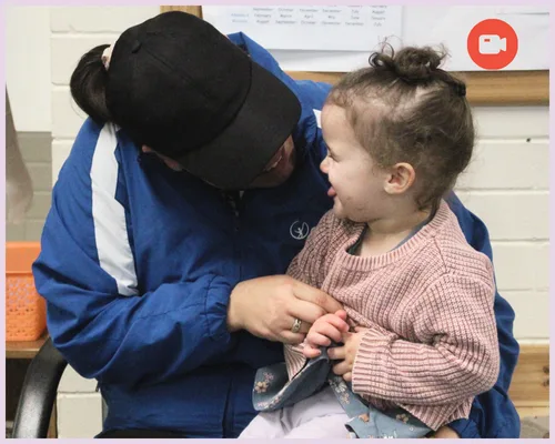 An educator and baby laugh together