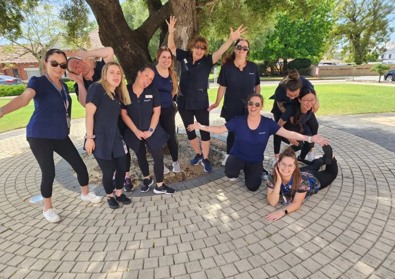 A group of women outside by a tree smiling for a photo