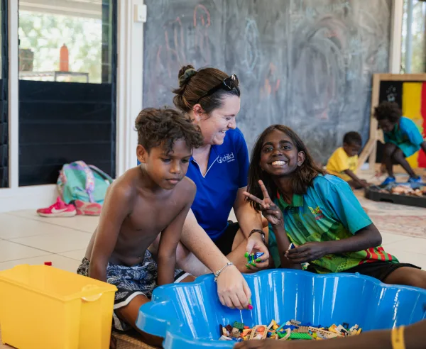 An educator and two children play with lego together