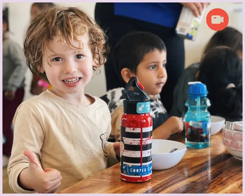 A child smiles whilst eating lunch