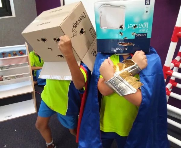 Two children with boxes on their head pretend to be robots and play