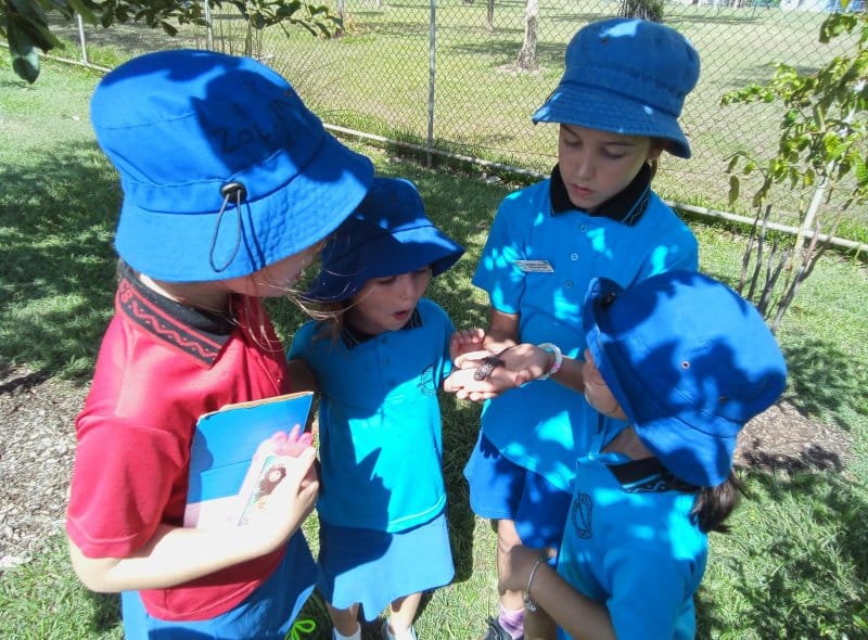 Children outside playing with a lizard