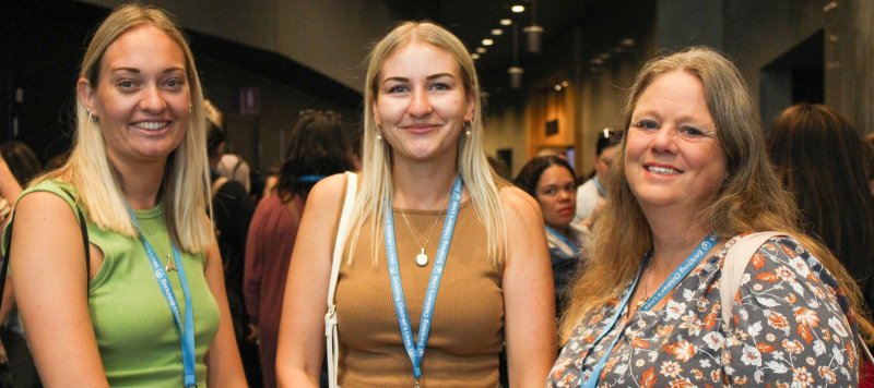 3 woman smile for a photo with lanyards around their neck