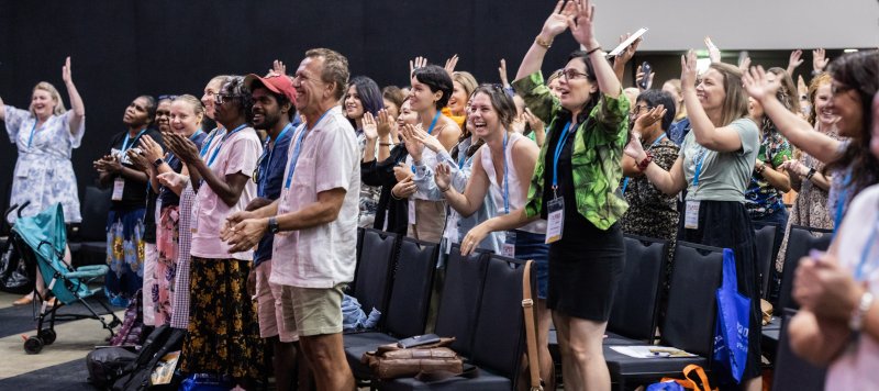 A group of people in an auditorium standing up from their chairs and dancing
