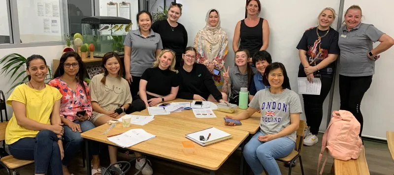 A group of staff members get together for a photo and smile inside