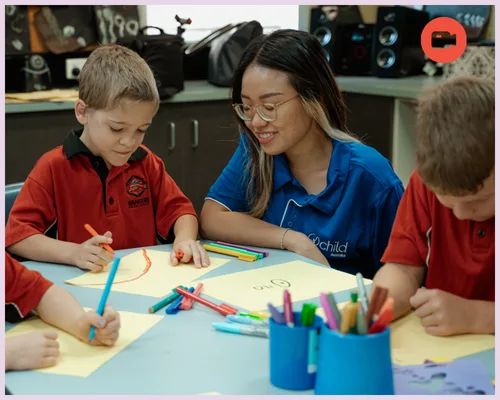 Outside School Hours Care - An educator watches the children draw