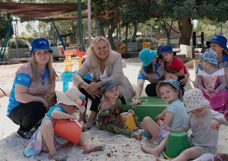 Children and educators building sandcastles in the sand pit