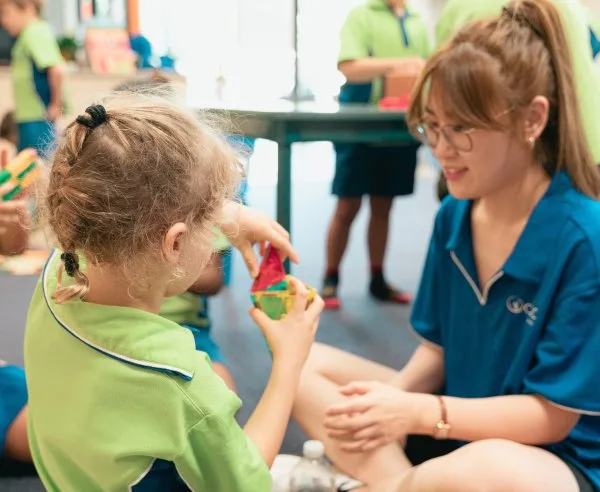 An educator and a child play with blocks together