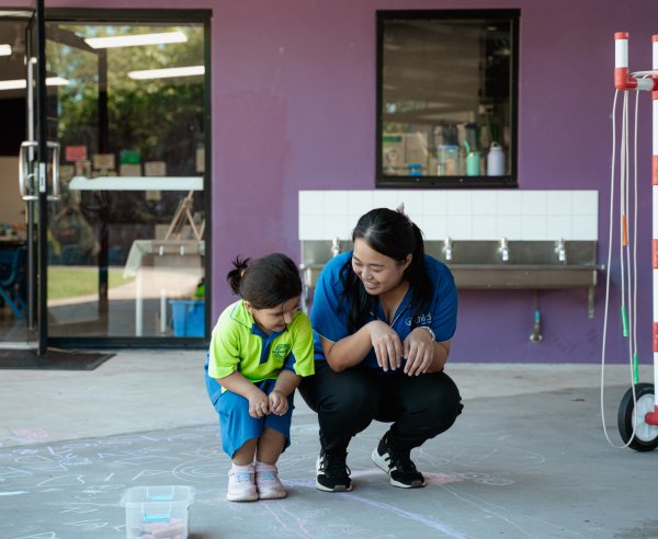 An educator and a child hop together outside