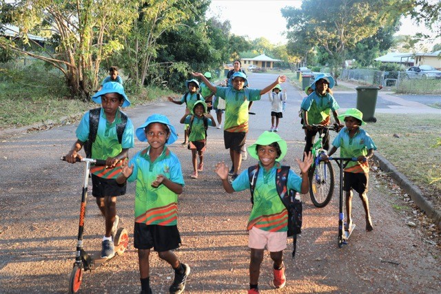 A group of kids running and playing on scooters and bikes