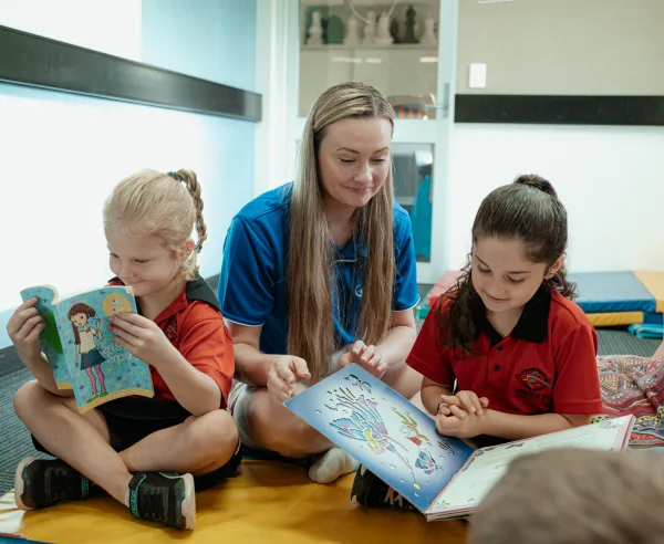 An educator and children read books together and smile