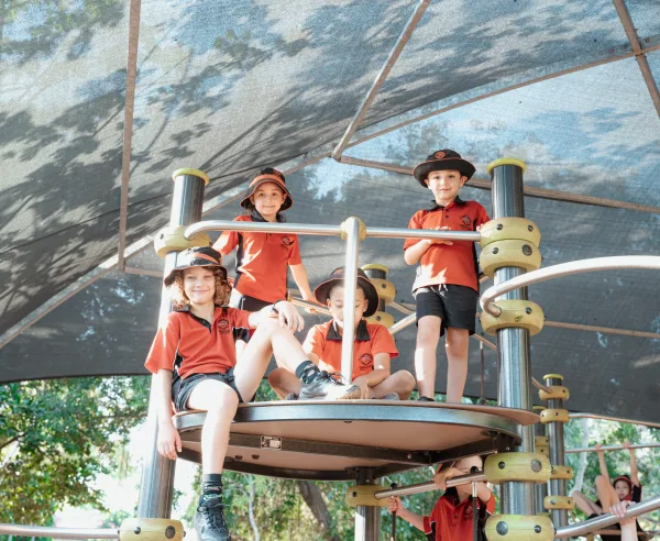 Children smile for a photo whilst standing on the playground