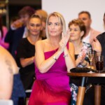 A woman claps at an awards show in a pink dress