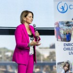 A woman speaks to an audience through a microphone