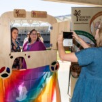 A woman takes a photo of two friends at an event