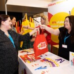 A woman hands out a 'Busy Bees' bag
